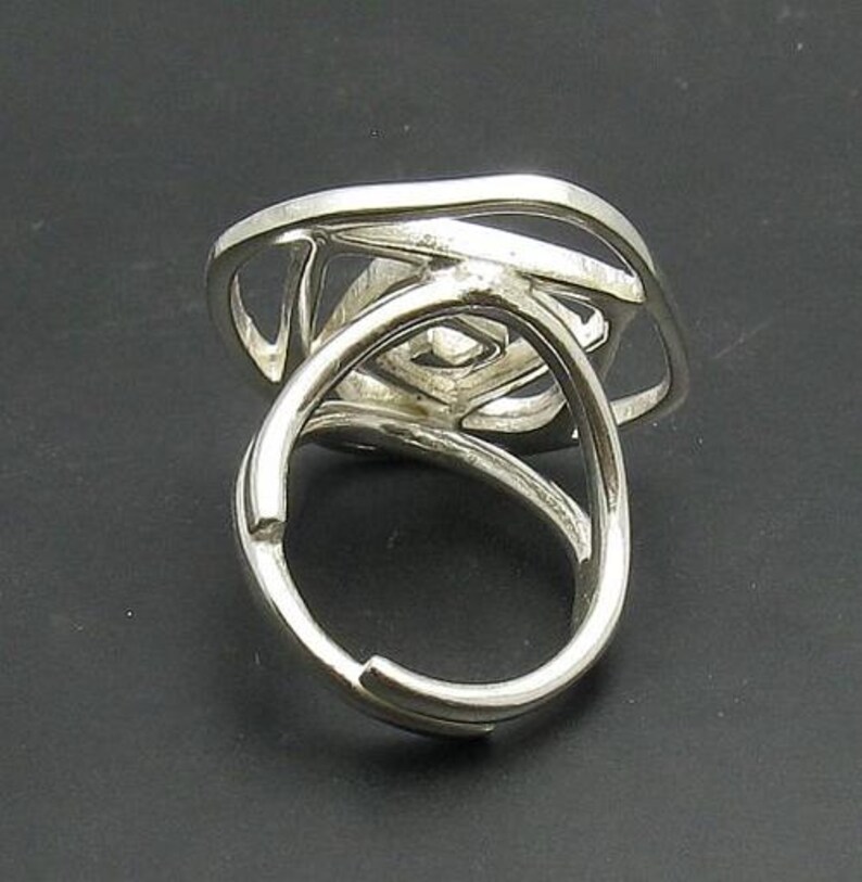 May include: A silver ring with a unique, abstract design. The ring is made of multiple intertwined bands that create a geometric pattern.