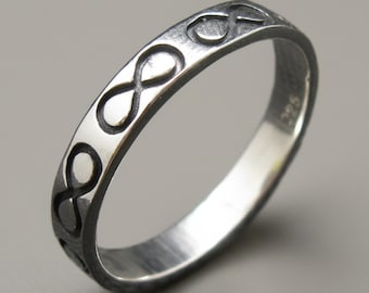 May include: A silver-toned metal ring featuring a repeating infinity symbol pattern engraved along the outer band. The ring has a dark, oxidized finish within the recessed areas of the design and a polished surface. The number 925 is stamped inside.