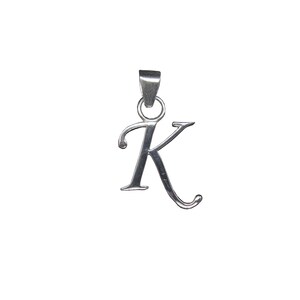 Könnte beinhalten: Ein silberfarbener Metallanhänger in Form des Großbuchstabens K in einer kursiven Schriftart. Der Anhänger hat eine glatte, polierte Oberfläche und verfügt über einen kleinen runden Ring an der Oberseite, der mit einer flachen, konischen Öse verbunden ist.