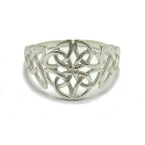 Puede incluir: Un anillo de plata con un intrincado diseño de nudo celta. El patrón calado del anillo muestra líneas entrelazadas que forman un motivo central en forma de flor, con nudos adicionales en los laterales. El anillo se muestra sobre un fondo blanco.