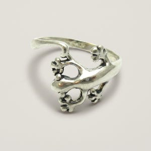 May include: A polished silver ring featuring a lizard design that wraps around the finger. The lizard has a smooth body, detailed toes, and a curved tail that forms the band of the ring. The metal has a bright, reflective finish throughout.