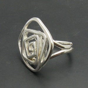 May include: A silver ring with a geometric design of overlapping squares. The ring is made of a smooth, polished metal and has a modern, minimalist style.