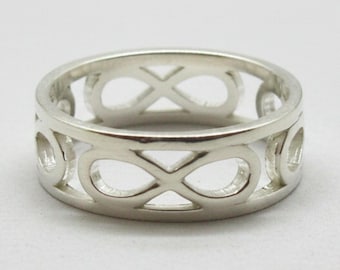 May include: A silver-toned ring featuring a continuous cut-out pattern of infinity symbols around the entire band. The metal has a smooth, polished finish, and the design consists of repeating horizontal figure-eight shapes linked together.