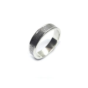 May include: A silver-toned metal ring featuring a textured, cross-hatched pattern along the outer band. The ring has a smooth, polished interior surface and a flat profile, showcasing a consistent width throughout the entire circumference of the band.