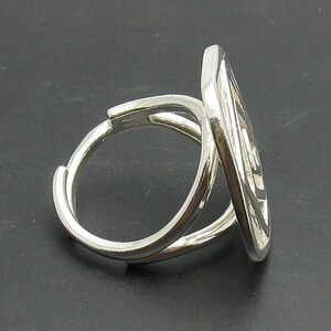 May include: A silver ring with a unique, intricate design. The ring is made of two bands that are intertwined and twisted together.