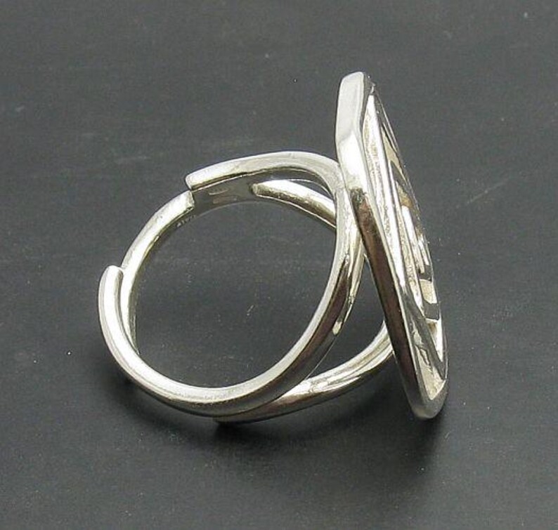 May include: A silver ring with a unique, intricate design. The ring is made of two bands that are intertwined and twisted together.