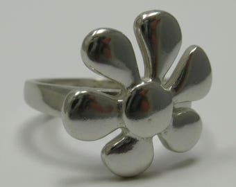 May include: A polished silver-toned ring featuring a prominent flower-shaped centrepiece. The floral design consists of six rounded, smooth petals radiating from a central circular point, all crafted with a reflective, metallic finish.