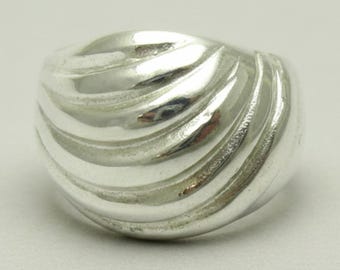 May include: A polished silver ring featuring a wide, domed band with a series of raised, curved ridges that sweep across the surface. The metal has a high-shine, reflective finish that highlights the smooth, undulating texture of the design.