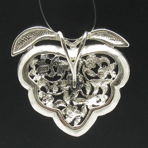 May include: Silver pendant featuring a delicate, intricate design resembling a cluster of leaves. The pendant is attached to a silver chain.