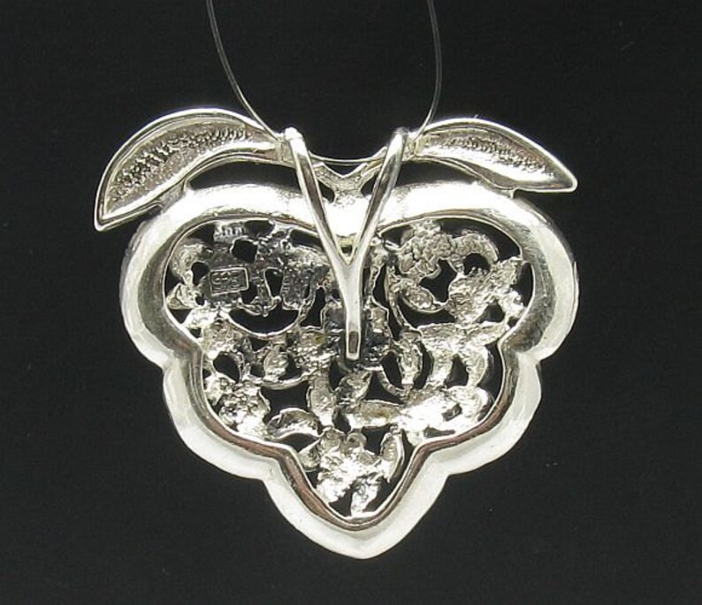 May include: Silver pendant featuring a delicate, intricate design resembling a cluster of leaves. The pendant is attached to a silver chain.