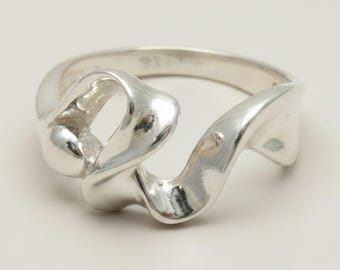 May include: A polished silver ring featuring a fluid, organic, and sculptural design. The band consists of smooth, undulating metal curves that wrap around the finger, creating an open, asymmetrical shape with a reflective, high-shine finish.