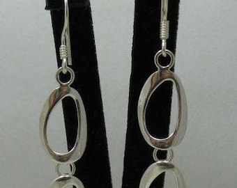 May include: A pair of silver-toned drop earrings featuring two vertically aligned, irregular oval-shaped open links. Each earring is suspended from a simple hook wire, showcasing a polished metallic finish and a clean, minimalist design structure.