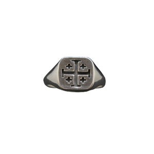 Könnte beinhalten: Ein silberfarbener Siegelring mit quadratischer Kopfplatte und eingraviertem Jerusalemkreuz. Die Metalloberfläche ist poliert, während die Vertiefungen des Kreuzsymbols dunkel abgesetzt sind, was einen deutlichen Kontrast auf dem Ringkopf erzeugt.