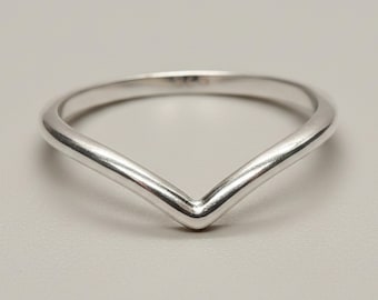 May include: A polished silver-toned V-shaped ring with a smooth, rounded band. The ring features a distinct chevron or pointed design that tapers toward the center, creating a clean, continuous metallic surface without any additional stones or engravings.