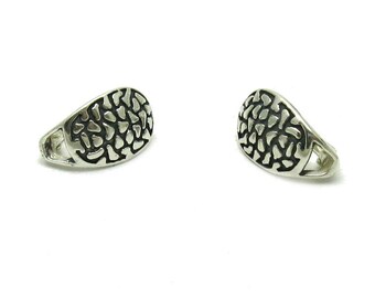 May include: A pair of silver-toned earrings featuring a semi-circular shape with a raised, textured pattern of irregular, dark-filled shapes across the surface. Each earring has a smooth, polished metal border and an open loop at the base.