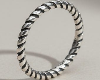 May include: A silver-colored ring featuring a continuous twisted rope texture throughout the entire band. The metal has a polished finish with darkened recessed areas between the twists to highlight the intricate rope-like pattern design.