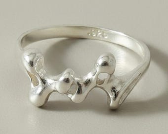 May include: A silver ring featuring an irregular, organic, molten-like design across the front. The band is smooth and polished, with the hallmark .925 clearly stamped on the interior surface, indicating the sterling silver composition of the piece.