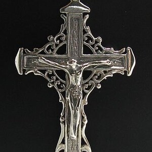 May include: A silver filigree cross pendant with a detailed depiction of Jesus Christ on the cross.