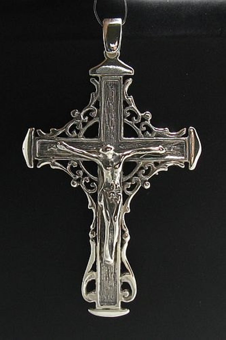 May include: A silver filigree cross pendant with a detailed depiction of Jesus Christ on the cross.