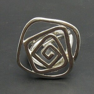 May include: Silver ring with a geometric design featuring multiple overlapping squares.