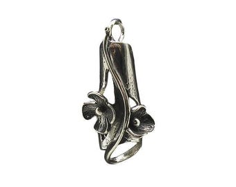 May include: A silver-toned metal pendant featuring a vertical, textured cylindrical form adorned with two sculpted flower blossoms. A slender, curved vine-like element wraps around the central structure, connecting to a small circular bail at the top.