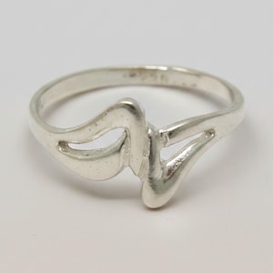 May include: A polished silver ring featuring a continuous, fluid, and abstract wave-like design that forms an open, asymmetrical shape across the top. The band is smooth and rounded, with the hallmark 925 clearly visible on the inner surface.