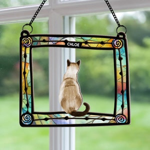 May include: A stained glass window hanging with a colorful frame and a cat silhouette inside. The cat is facing away from the viewer and the name "CHLOE" is written at the top of the frame.