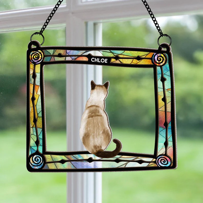 May include: A stained glass window hanging with a colorful frame and a cat silhouette inside. The cat is facing away from the viewer and the name "CHLOE" is written at the top of the frame.