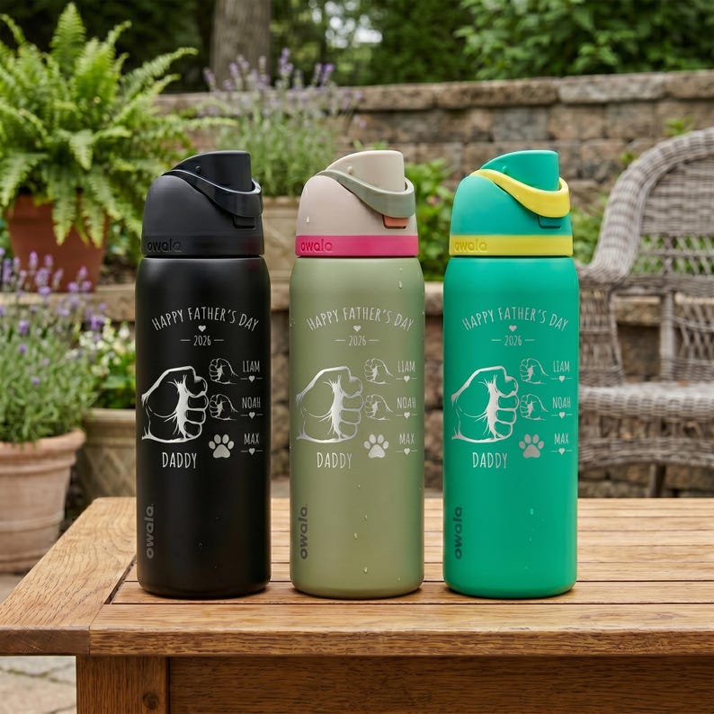 May include: Three insulated water bottles in black, olive green, and teal, each with a flip-top lid. The bottles are decorated with the text "Happy Father's Day - 2026" and a graphic of a hand, paw prints, and the names Liam, Noah, and Max.