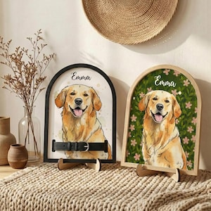 May include: Two arched wooden signs featuring watercolor portraits of a Golden Retriever dog. One sign has a black frame and a black leather collar. The other has a light wood frame with a floral background. Both signs have the name "Emma" at the top.