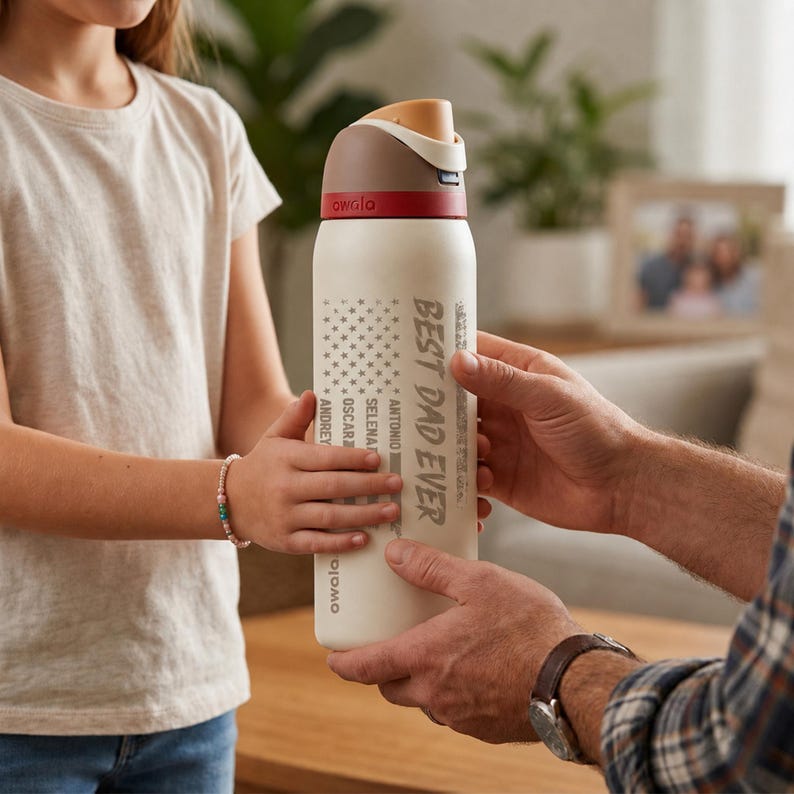 Puede incluir: Una botella de agua aislada blanca con una tapa marr&oacute;n y roja est&aacute; siendo sostenida por dos personas. La botella tiene el texto "BEST DAD EVER" y un dise&ntilde;o de estrellas. La botella tambi&eacute;n tiene los nombres "ANDREY", "OSCAR", "SELENA" y "ANTONIO".