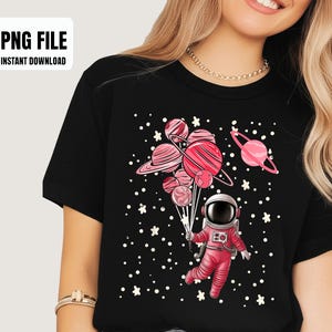 May include: Black t-shirt featuring a pink astronaut holding planet-shaped balloons. The design includes pink planets, stars, and the text "PNG FILE INSTANT DOWNLOAD". A fun, space-themed graphic tee.