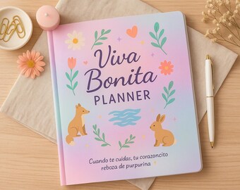 May include: A planner titled "Viva Bonita Planner" with a pastel gradient cover, featuring floral and animal illustrations. Includes a white pen, a small dish with gold paper clips, a pink candle, and a decorative flower. The planner has text in Spanish.