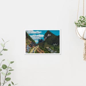 May include: A framed landscape painting depicts a winding road through a mountain range. The artwork features a blue sky with fluffy white clouds, green hills, and a few vehicles traveling on the road. A small village is nestled in the valley.