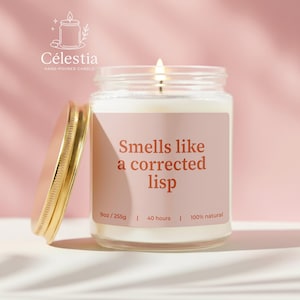 May include: A lit, hand-poured candle in a glass jar with a gold lid. The label reads "Smells like a corrected lisp." The candle is 9oz/255g and burns for 40 hours. The brand name "Célestia" is at the top.