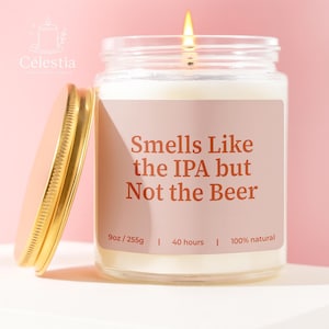 May include: A lit, scented candle in a glass jar with a gold lid. The label reads "Smells Like the IPA but Not the Beer." The candle is 9oz/255g and burns for 40 hours. The candle is 100% natural.