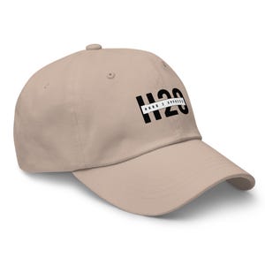 Könnte beinhalten: Beige Baseball Cap mit dem Text "H2O HARD 2 OPPRESS" in Schwarz und Weiß. Der Hut besteht aus einem weichen Material und hat einen gebogenen Schirm. Die Kappe ist nach rechts abgewinkelt und zeigt den Text auf der Vorderseite.
