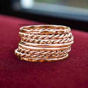 May include: A stack of seven rose gold rings featuring alternating textures, including smooth bands, twisted rope designs, and hammered finishes. The text GargiPinkCityStore is visible above the stack of rings, which are arranged in a vertical column.