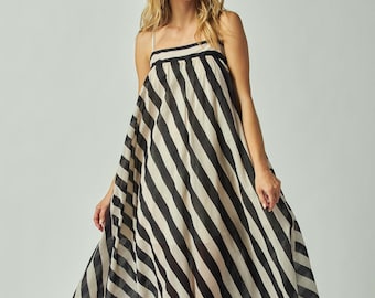 May include: A floor-length, sleeveless dress with a black and off-white striped pattern. The dress features a square neckline and thin straps. The fabric drapes loosely, creating a flowing silhouette. The dress is suitable for casual or semi-formal occasions.