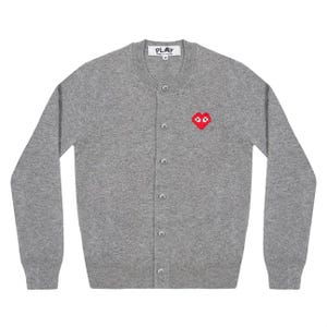 May include: A gray cardigan sweater with a red heart-shaped graphic on the left chest. The sweater has a button-up front and long sleeves. The brand name "PLAY" is visible on the neckline.