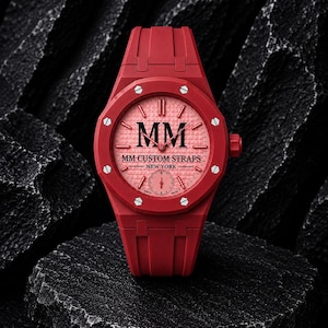 Könnte beinhalten: Eine rote Armbanduhr mit einem strukturierten roten Zifferblatt, das den schwarzen Schriftzug MM, MM CUSTOM STRAPS und NEW YORK trägt. Die Uhr hat eine rote achteckige Lünette mit acht silberfarbenen Schrauben, ein rotes Kautschukarmband.