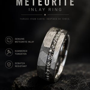 Può includere: Un anello in tungsteno martellato grigio con un intarsio centrale in meteorite autentico. Il testo sull'immagine recita: HAMMERED TUNGSTEN METEORITE INLAY RING, FORGED FROM EARTH. INSPIRED BY SPACE., GENUINE METEORITE INLAY, HAMMERED TUNGSTEN, SCRATCH RESISTANT, RARE. STRONG. TIMELESS.