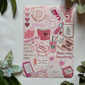 Peut inclure: Une planche d'autocollants rectangulaire sur fond rose avec diverses illustrations dont une canette de Diet Coke, un Bisounours, un téléphone à clapet, une carte de bibliothèque, un café et des textes comme Kindle girl era, low social battery et girl dinner.