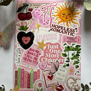 Op de afbeelding: Een stickervel met een roze achtergrond en diverse illustraties waaronder een zon, kersen, dobbelstenen, een vinylplaat, boeken, een kamerplant, vlinders en tekst zoals "Hopeless Romantic", "I'd Rather Be Reading" en "Just One More Chapter".