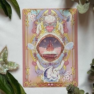 Peut inclure: Une impression d'art rectangulaire avec un cadre circulaire central contenant un château rose posé sur un livre ouvert. La bordure est ornée de filigrane doré, de fleurs roses, d'un chat blanc endormi sur un croissant de lune et du texte 'THINGS TO LOVERS'.