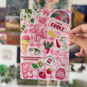 Könnte beinhalten: Ein rechteckiger Aufkleberbogen mit einem rosa-weiß karierten Hintergrund, der verschiedene Illustrationen zeigt, darunter eine Discokugel, ein Ballonhund, ein Kaktus, ein Gummibärchen, eine Erdbeere, eine Sprühflasche und Katzen mit Text.