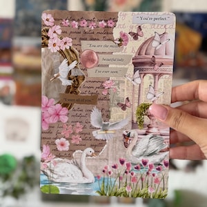 Könnte beinhalten: Eine rechteckige Collage-Karte mit weißen Schwänen, fliegenden weißen Tauben, rosa Blumen und Schmetterlingen. Der Hintergrund zeigt Vintage-Schrift, einen goldenen Rahmen und eine Pavillon-Illustration. Textstreifen lauten: You're perfect, You are the most beautiful lady, I've ever seen und I want all of you.