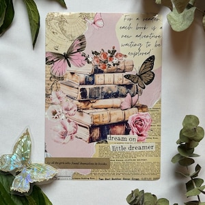 Op de afbeelding: Een rechthoekige collage-print met een stapel vintage boeken, roze en bruine vlinders en bloemenillustraties. De tekst luidt: For a reader, each book is a new adventure waiting to be explored, dream on, little dreamer en meer.