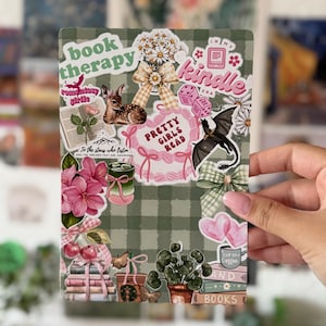 Pode incluir: Um cartão retangular com fundo xadrez verde-sálvia, apresentando vários adesivos, incluindo textos que dizem book therapy, kindle, pretty girls read e to the stars who listen. As ilustrações incluem um cervo, um dragão, flores e livros.