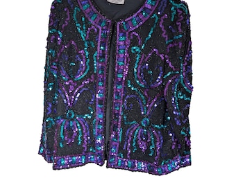 Jaqueta vintage Laurence Kazar com lantejoulas e miçangas nas cores roxo, verde-azulado e preto, estilo blazer aberto na frente.